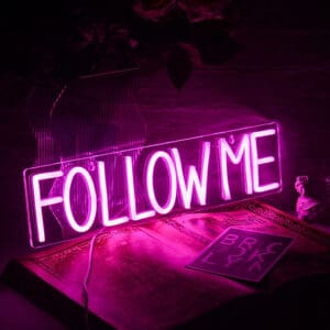 Pink wording Follow Me Neon Sign in block lettering in an acrylic frame